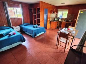 a bedroom with two beds and a table and a kitchen at Cabaña Itia in Hanga Roa