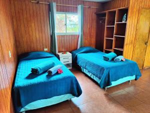 two beds in a room with blue sheets and towels at Cabaña Itia in Hanga Roa