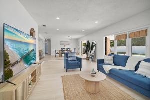 a living room with a blue couch and a tv at Relaxing Coastal POOL Home 10 min to the Beach Pets stay free in Palm Coast