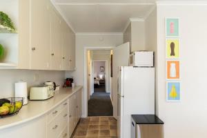 une cuisine avec des armoires blanches et un réfrigérateur blanc dans l'établissement Cute on Konene - Quiet & Central Family ready, à Rotorua