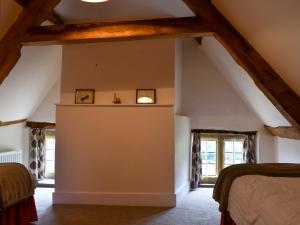 Wootton Glanville丘吉尔乡村别墅的阁楼卧室，有外露的横梁和窗户