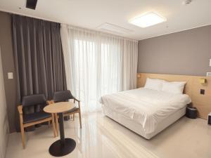 a bedroom with a bed and a table and a chair at Sokcho Whalejib The Blue Terra Ocean Stay in Puwŏl-li