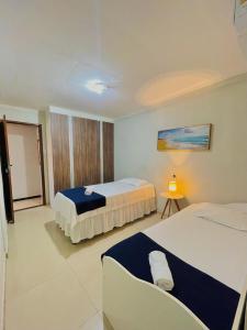 a hotel room with two beds and a table at Residencial Temporada Aracaju in Aracaju