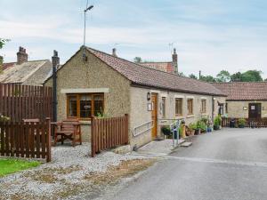 ein Haus mit einem Holzzaun neben einer Straße in der Unterkunft Swallowtail Cottage - Uk2296 in Ebberston