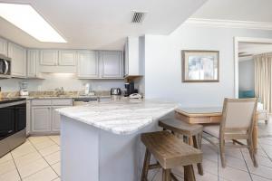 a kitchen with white cabinets and a table and chairs at Phoenix VI 61004 in Orange Beach