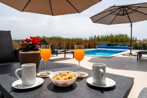 een tafel met twee glazen sinaasappelsap en een kom eten bij Villa Anabel in Privlaka