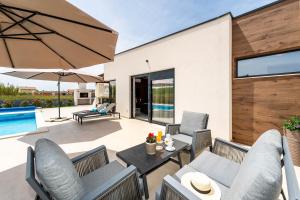 een terras met stoelen, een tafel en een parasol bij Villa Anabel in Privlaka