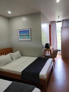 a bedroom with a bed and a table and a chair at Mamay's Place Homestay in Tagbilaran City