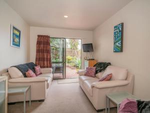 a living room with two couches and a sliding glass door at The Harbour View Tairua in Tairua