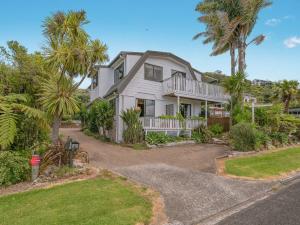 a house with palm trees and a driveway at The Harbour View Tairua in Tairua