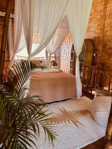 ウルワツにあるCasa Bamboo uluwatu 2のベッドルーム1室(カーテン、植物付)