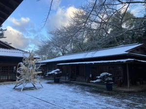 ein Haus mit einem schneebedeckten Hof und einer Skulptur in der Unterkunft Oukai Villa Izumi in Izumi