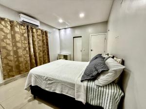 a bedroom with a bed with white sheets and curtains at Casa da Anita in Boa Vista