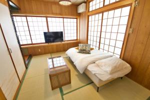 ein Zimmer mit einem Bett und einem Tisch und Fenstern in der Unterkunft 北谷町宮城戸建て in Hamakawa + 61 Fotos