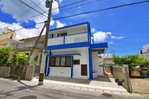 ein blau-weißes Haus an der Straßenseite in der Unterkunft 北谷町宮城戸建て in Hamakawa