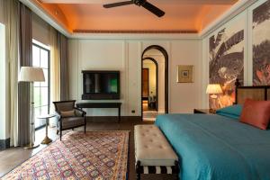 a bedroom with a bed and a desk and a tv at The Oberoi Rajgarh Palace in Rājgarh