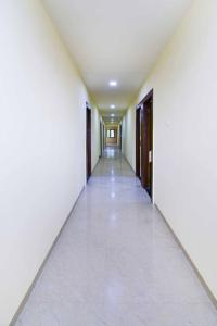 an empty corridor with white walls and a long hallway at Hotel O Gokul Lodging in Pune