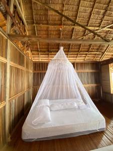 a bed in a straw hut with a net at Senjahomestayrajaampat in Fam