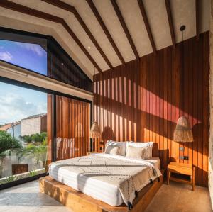 a bedroom with a bed and a large window at Blacksand Villas Bingin, Uluwatu by Sandara in Uluwatu