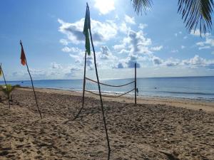 a volleyball net on a beach with the ocean at Pousada Sol de Berlinque in Vera Cruz de Itaparica