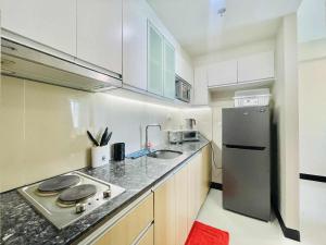 a small kitchen with a sink and a refrigerator at Heart of Mactan Newtown big space with free wifi and pool access in Punta Engaño