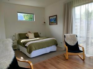 a bedroom with a bed and a chair and a window at Gills Hawea Haven in Lake Hawea