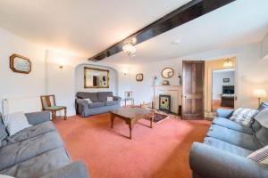 a living room with blue couches and a table at Park Farmhouse in Chideock