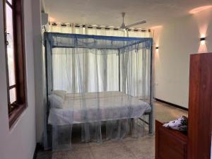 a bedroom with a bed with a canopy and a window at Sri Holiday House - Hikkaduwa in Hikkaduwa