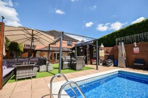 a backyard with a swimming pool and an umbrella at Freshwinds in Market Drayton