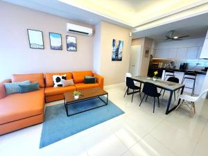 Una sala de estar con un sofá naranja y una mesa. en The Azure Residences, en Kampong Baharu Sungai Way