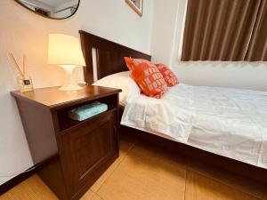 a bedroom with a bed and a table with a lamp at Rest Collection SEIWA LODGE Tokyo in Tokyo