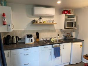 a kitchen with white cabinets and a sink and a microwave at Willows Reach Lodge in Kumeu