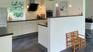 une cuisine avec des armoires blanches et un comptoir avec une chaise dans l'établissement Family Cottage At Odden, 100 Meters From The Beach, à Lumsås