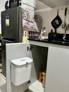 a small kitchen with a white toilet and a refrigerator at The Merry Meg Residences in Mandaue City