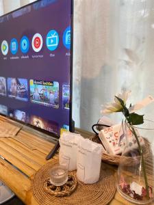 a desk with a monitor and a vase with a flower at baan in kan homestay&cafe kanchanaburi city in Kanchanaburi