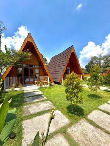 a large wooden house with a grass yard at Rinjani view bungalow in Masbagik