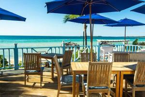 a table and chairs with blue umbrellas and the beach at Cocodimama small - Boutique Resort on Spectacular Beach Hotel Room in Governors Harbour