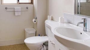 a white bathroom with a toilet and a sink at Del Rae Unit 8 25 Shoal Bay Road in Shoal Bay +10 photos