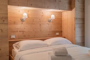 a bedroom with a bed with two pillows and two lights at Alpine Heart in Falcade