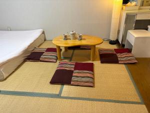 a room with a table and three rugs on the floor at hostel sunflower202 in Osaka