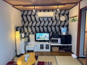a living room with a tv on a wall at hostel sunflower202 in Osaka