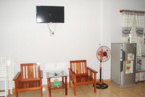 Zimmer mit 2 Stühlen, einem TV und einem Kühlschrank in der Unterkunft De Vong Riverside Homestay in Hoi An
