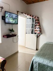 サユリタにあるCasa Baluana vive Sayulita a un paso de todoのベッド1台と壁掛けテレビが備わる客室です。