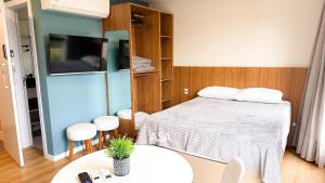 um pequeno quarto com uma cama e uma televisão em ASA | Loft UP 309 | Lado da FURB | Oktoberfest em Blumenau