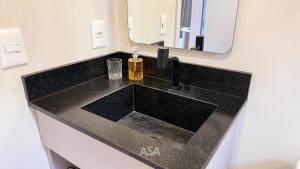 um lavatório preto na casa de banho com um espelho em ASA | Loft UP 309 | Lado da FURB | Oktoberfest em Blumenau mais 13 fotografias