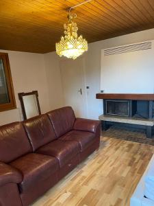 a brown leather couch in a living room with a fireplace at Rooms for rent in Bolligen in Bolligen