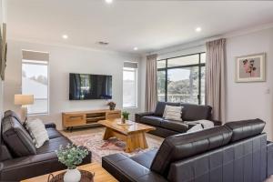 un soggiorno con 2 divani in pelle e una TV di Wildgreen Villa - Lakeside Hideaway in Winery Estate a Yallingup Siding