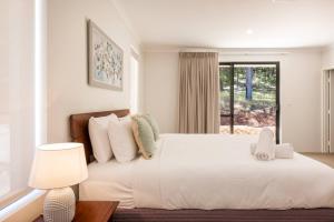 una camera da letto con un grande letto bianco con una finestra di Wildgreen Villa - Lakeside Hideaway in Winery Estate a Yallingup Siding