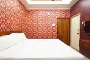 1 dormitorio con cama y papel pintado de color rojo en Easwarresidency, en Chennai 5 fotos más