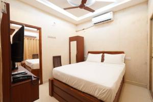 Un dormitorio con una cama y un televisor. en Easwarresidency, en Chennai